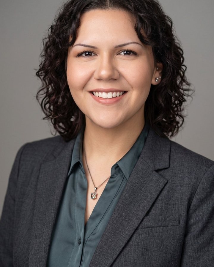 Natalia Quintero, principal of Superlative Advisory, in a charcoal blazer against a grey backdrop